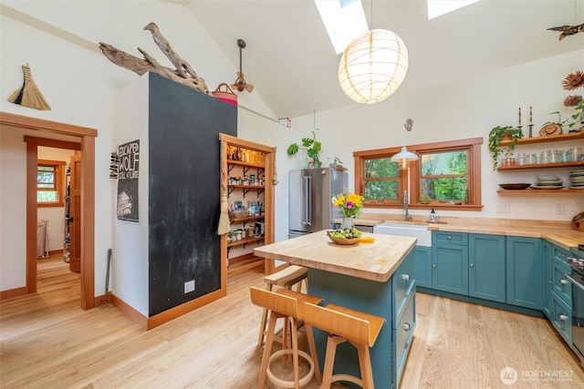 1692 Galbraith Ln, Bellingham, WA 98229 - kitchen featuring wooden counters, blue cabinetry, light wood-style flooring, plenty of natural light, and high vaulted ceiling