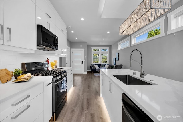 1315 Astor St, Bellingham, WA 98225 - kitchen with gas range oven, recessed lighting, light wood-style flooring, white cabinets, and decorative backsplash