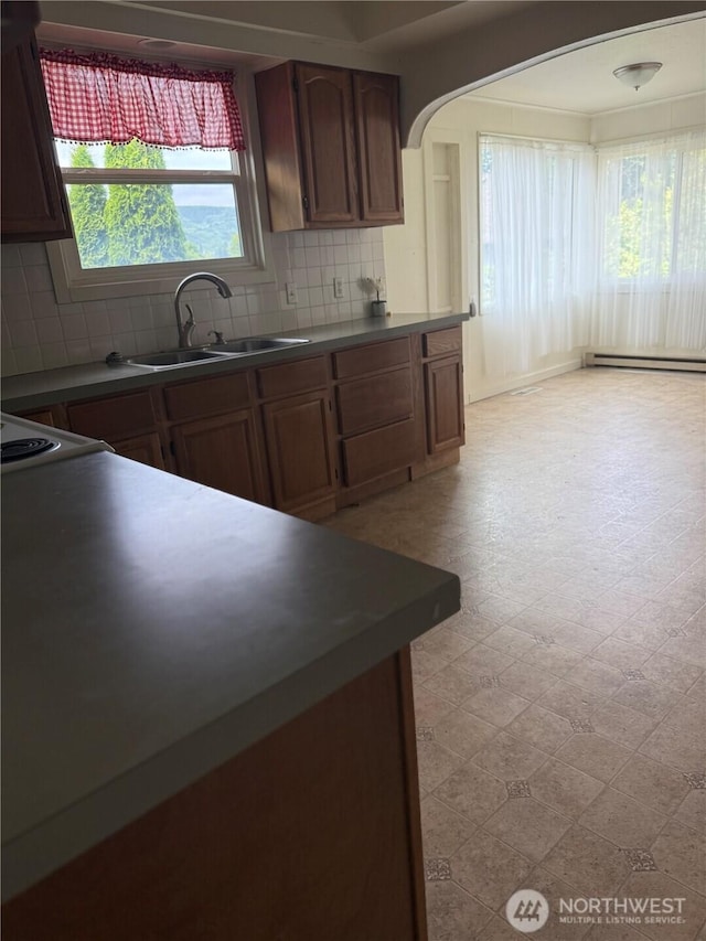 1019 Duryea St, Raymond, WA 98577 - kitchen with light floors, backsplash, arched walkways, and baseboard heating