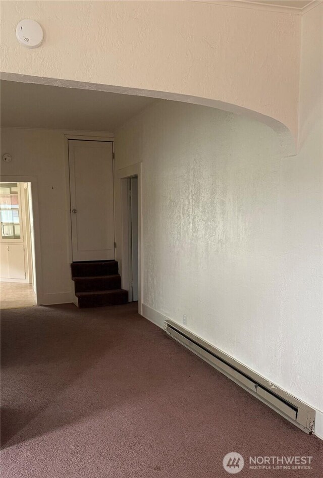 1019 Duryea St, Raymond, WA 98577 - unfurnished room with baseboard heating, dark carpet, stairs, a smoke detector, and a textured wall
