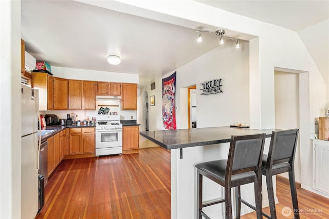 2639 Yew St, Bellingham, WA 98226 - kitchen with white range with gas cooktop, under cabinet range hood, a breakfast bar area, and dark countertops