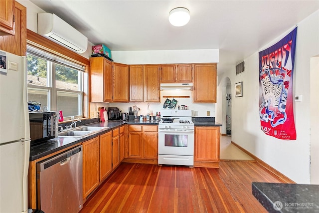 2639 Yew St, Bellingham, WA 98226 - kitchen featuring white appliances, arched walkways, dark countertops, dark wood-style flooring, and a wall mounted AC