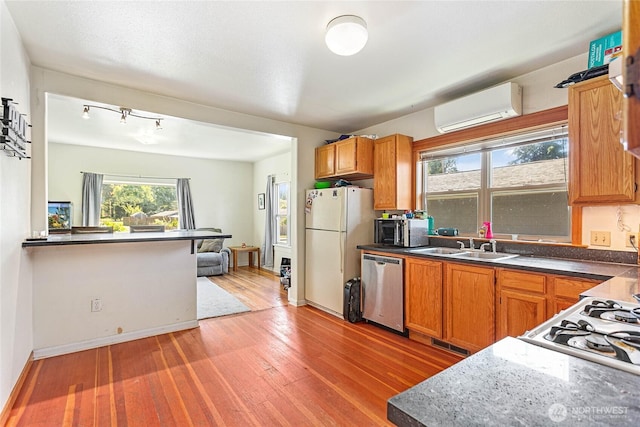 2639 Yew St, Bellingham, WA 98226 - kitchen featuring a wall mounted AC, stainless steel dishwasher, freestanding refrigerator, light wood-style floors, and dark countertops