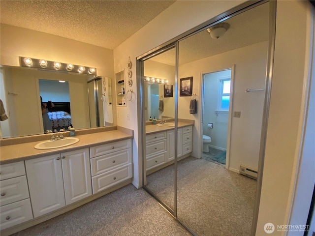 1051 Ocean Shores Blvd SW Unit 1B, Ocean Shores, WA 98569 - bathroom featuring ensuite bathroom, vanity, a textured ceiling, a baseboard radiator, and carpet floors