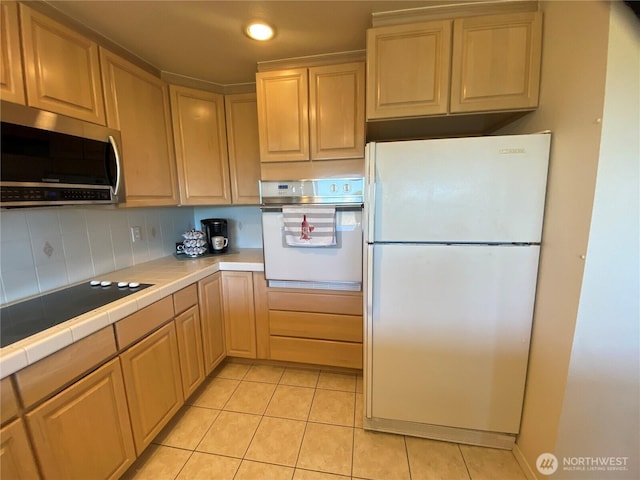 1051 Ocean Shores Blvd SW Unit 1B, Ocean Shores, WA 98569 - kitchen featuring white appliances, tile countertops, light tile patterned floors, and backsplash