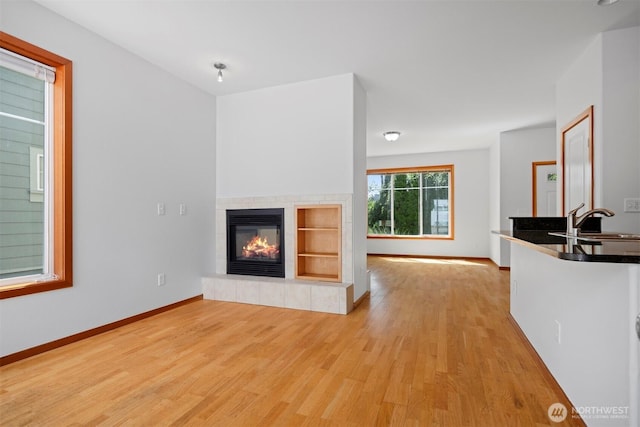 6214 Malloy Ave, Ferndale, WA 98248 - unfurnished living room with light wood-type flooring, a tiled fireplace, and built in features