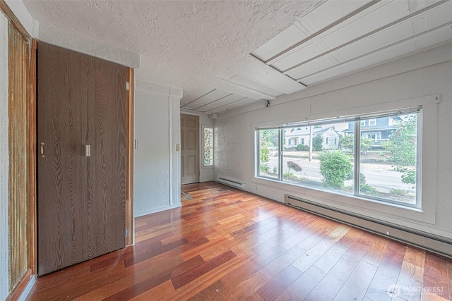 5507 N 45th St, Tacoma, WA 98407 - unfurnished room with a textured ceiling, wood finished floors, baseboard heating, and plenty of natural light