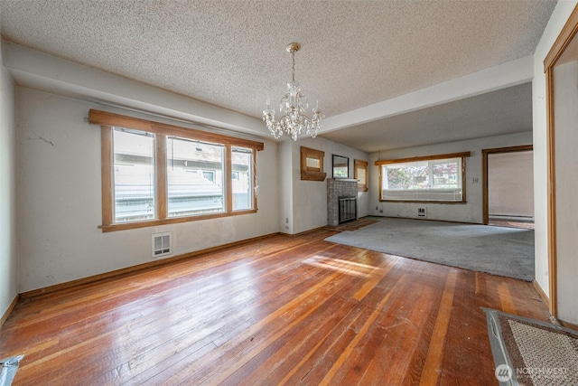 5507 N 45th St, Tacoma, WA 98407 - unfurnished living room featuring a textured ceiling, a chandelier, wood-type flooring, and a fireplace