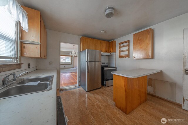 5507 N 45th St, Tacoma, WA 98407 - kitchen with stainless steel appliances, light wood-style flooring, light countertops, a chandelier, and brown cabinetry