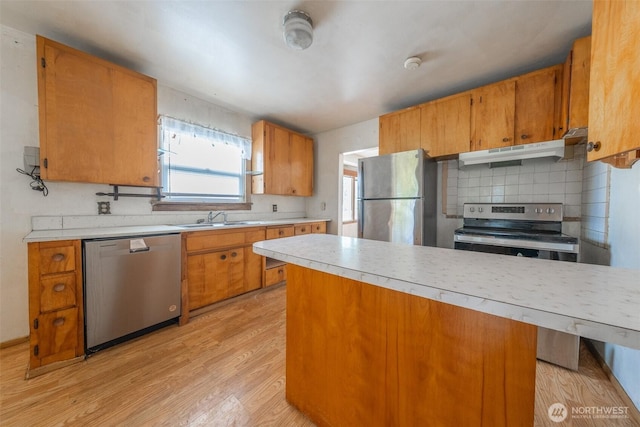 5507 N 45th St, Tacoma, WA 98407 - kitchen featuring light countertops, light wood-style floors, stainless steel appliances, brown cabinets, and backsplash