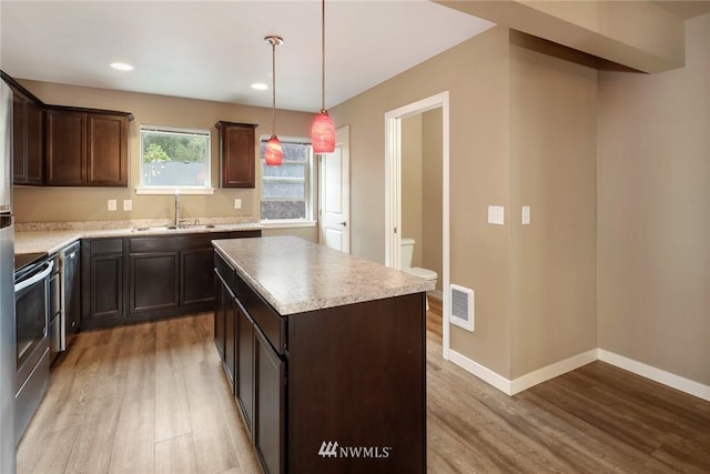 kitchen with light hardwood / wood-style floors, hanging light fixtures, sink, and a center island