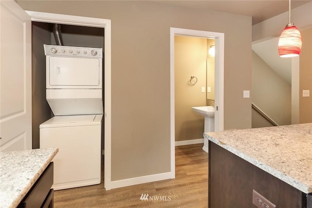 washroom featuring stacked washer and clothes dryer, light wood-type flooring, and sink