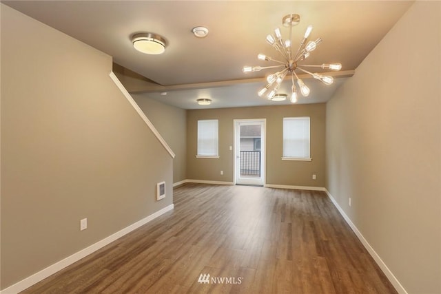 spare room featuring a notable chandelier and dark hardwood / wood-style flooring