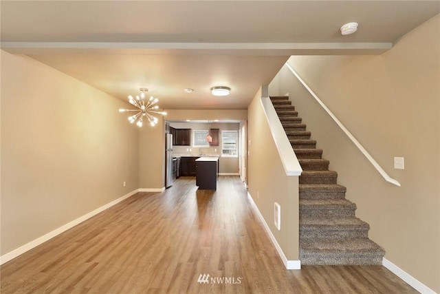 stairs with an inviting chandelier and light wood-type flooring