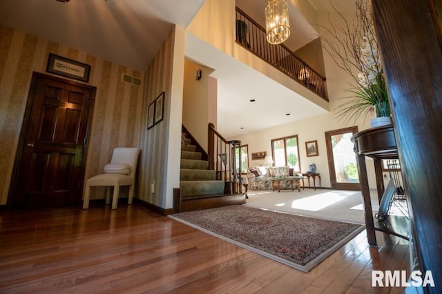 foyer featuring dark wood-type flooring, a chandelier, and a towering ceiling