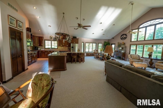 carpeted living room featuring ceiling fan, high vaulted ceiling, and a wealth of natural light