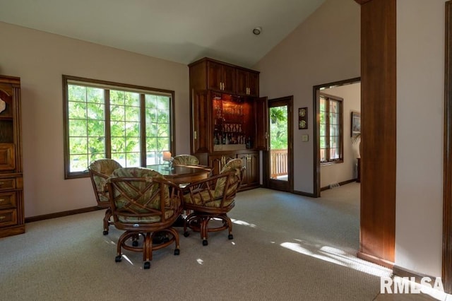 dining space featuring light colored carpet and high vaulted ceiling