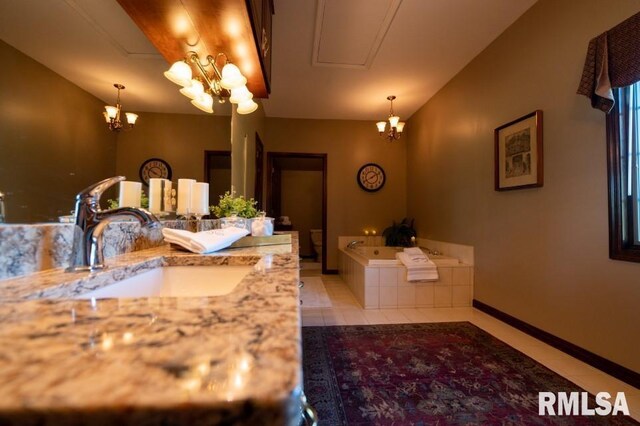 bathroom featuring an inviting chandelier, vanity, tile floors, and a bath to relax in