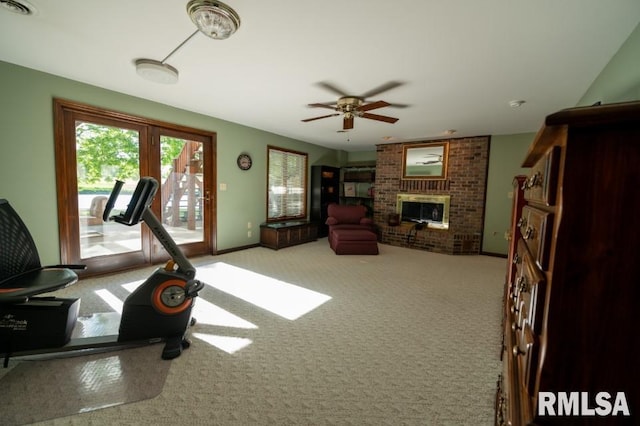 exercise room featuring a fireplace, ceiling fan, and light colored carpet