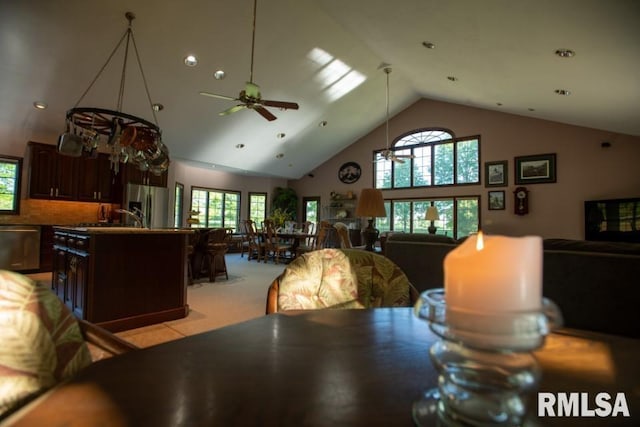 carpeted dining space with ceiling fan and high vaulted ceiling