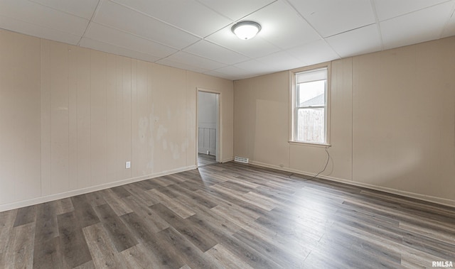 unfurnished room with dark hardwood / wood-style flooring and a drop ceiling