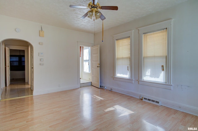 empty room featuring ceiling fan, light hardwood / wood-style flooring, and a textured ceiling