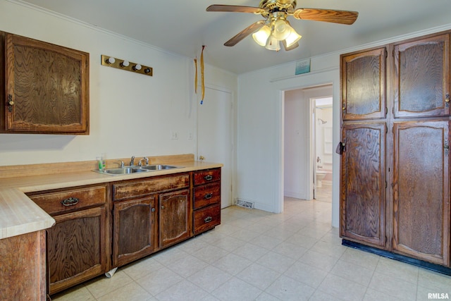 kitchen featuring crown molding, ceiling fan, sink, and light tile flooring