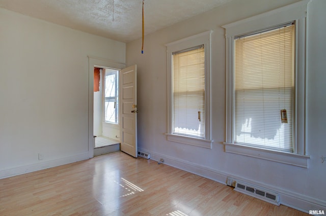 spare room featuring light hardwood / wood-style flooring and a textured ceiling