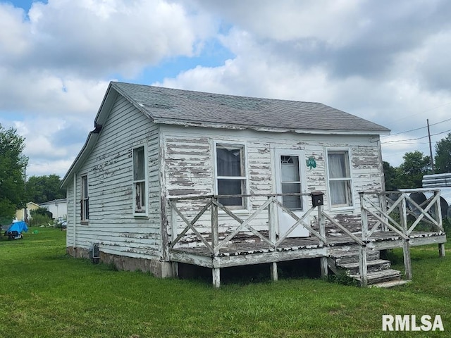 back of property with a deck and a yard