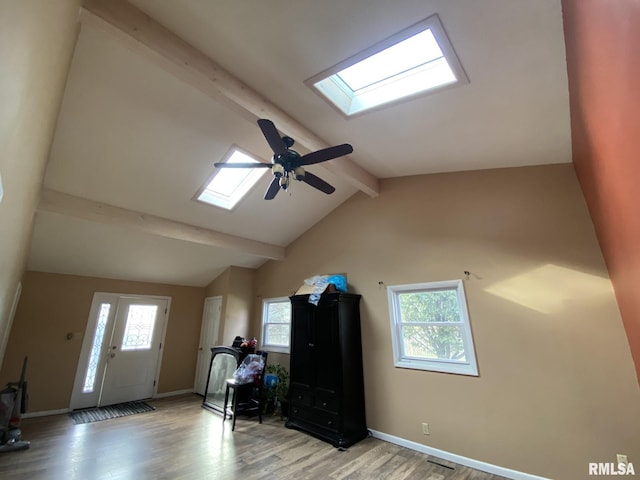 interior space with ceiling fan, vaulted ceiling with skylight, a wealth of natural light, and light hardwood / wood-style floors