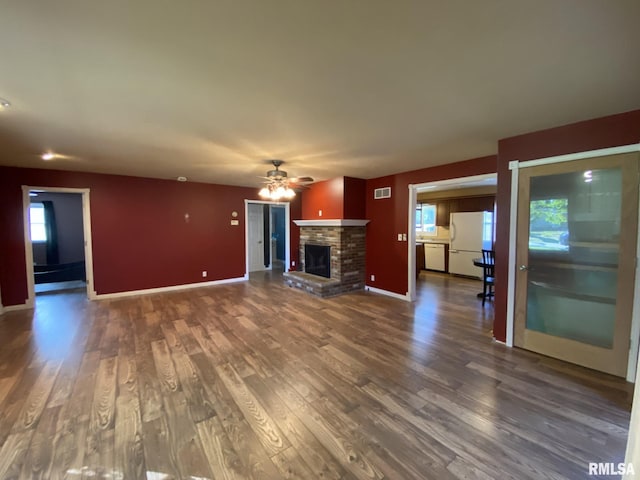 unfurnished living room with dark wood-type flooring, ceiling fan, and a brick fireplace