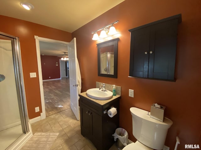 bathroom with ceiling fan, vanity, an enclosed shower, and toilet