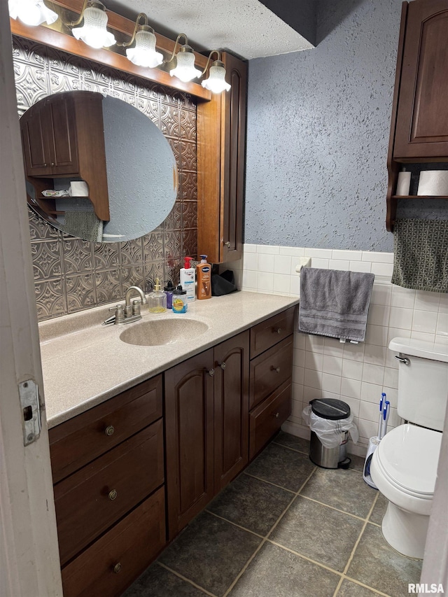 bathroom featuring vanity, toilet, and tile walls