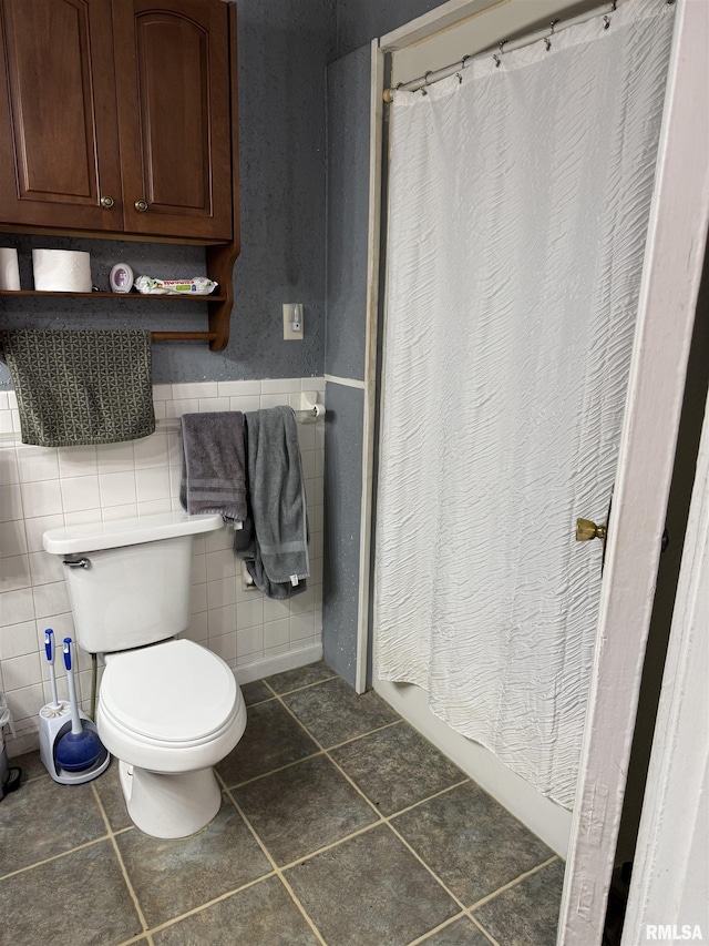 bathroom featuring a shower with shower curtain, tile patterned flooring, toilet, and tile walls