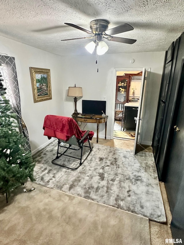 sitting room with ceiling fan, carpet floors, and a textured ceiling