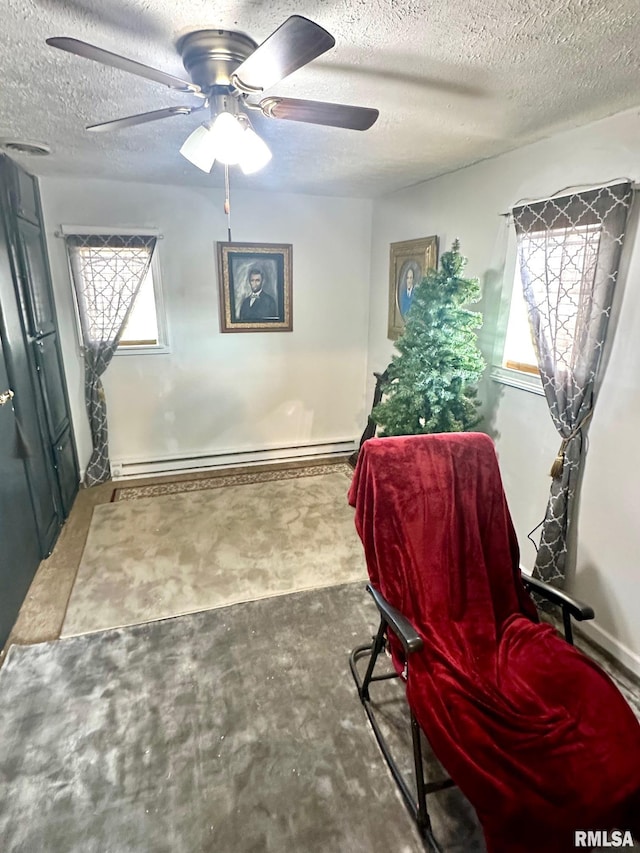 sitting room with a textured ceiling, a baseboard radiator, a wealth of natural light, and ceiling fan