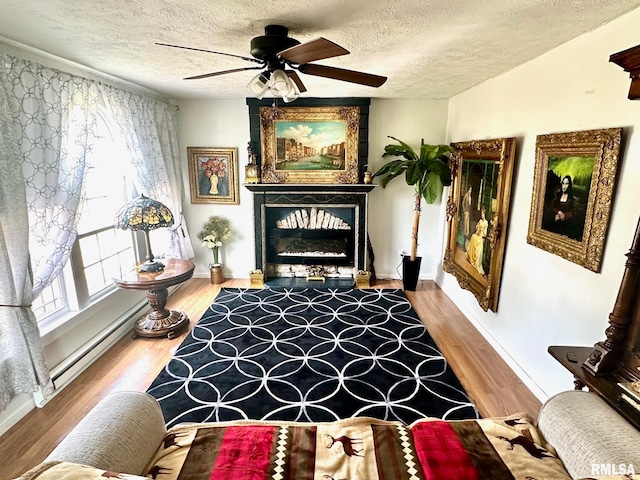 sitting room with a fireplace, ceiling fan, wood-type flooring, and a textured ceiling