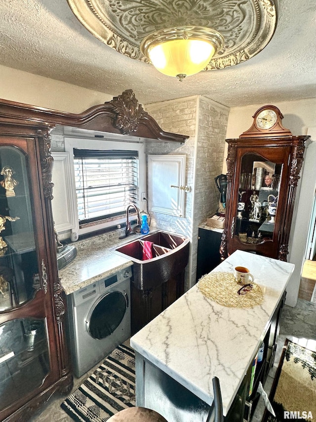 kitchen with a kitchen bar, light stone countertops, a center island, and washer / dryer