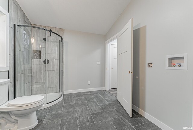 bathroom featuring a shower with shower door and toilet