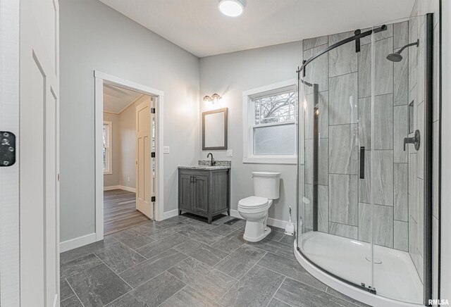 bathroom featuring vanity, toilet, and a shower with door