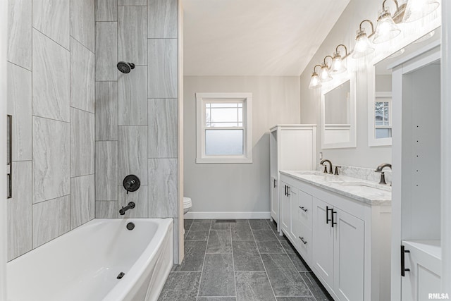 full bathroom featuring vanity, tiled shower / bath, and toilet