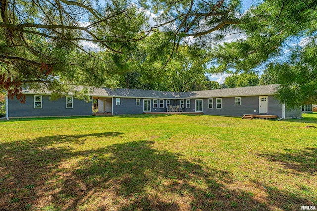 back of property featuring a wooden deck and a lawn