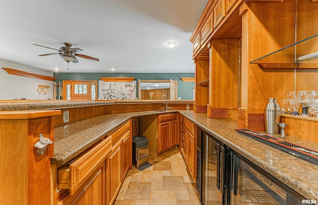 bar with sink, stone countertops, ceiling fan, and wine cooler