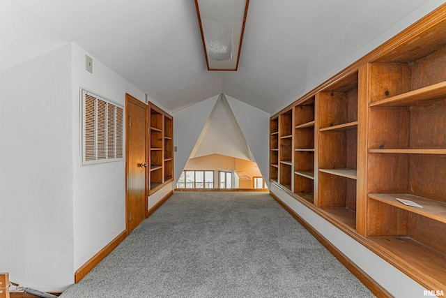 carpeted empty room featuring built in shelves and lofted ceiling