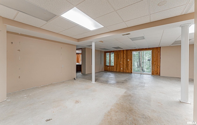 basement with a paneled ceiling and wood walls