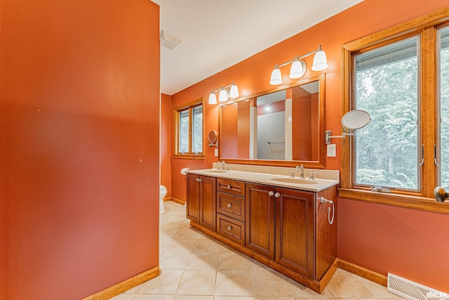 bathroom with a wealth of natural light, toilet, vanity, and tile patterned flooring