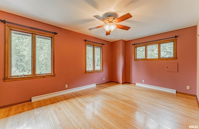 unfurnished room with baseboard heating, light hardwood / wood-style flooring, and a wealth of natural light