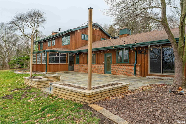 rear view of property with a patio area, a sunroom, and a lawn