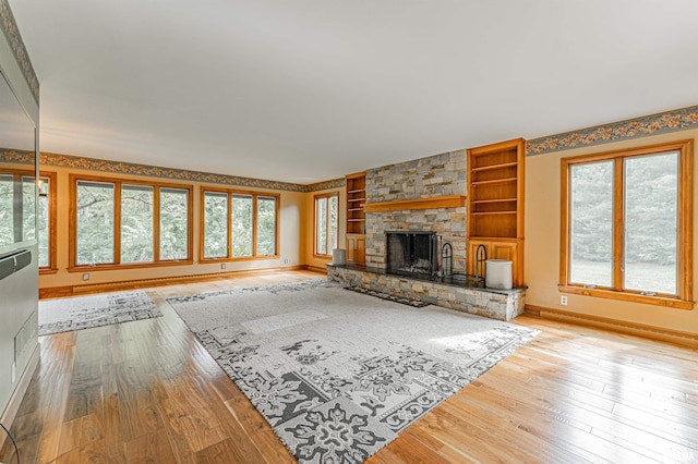 unfurnished living room with built in features, light wood-type flooring, and a healthy amount of sunlight