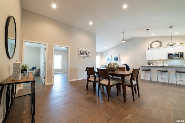 dining area with high vaulted ceiling, sink, and hardwood / wood-style floors